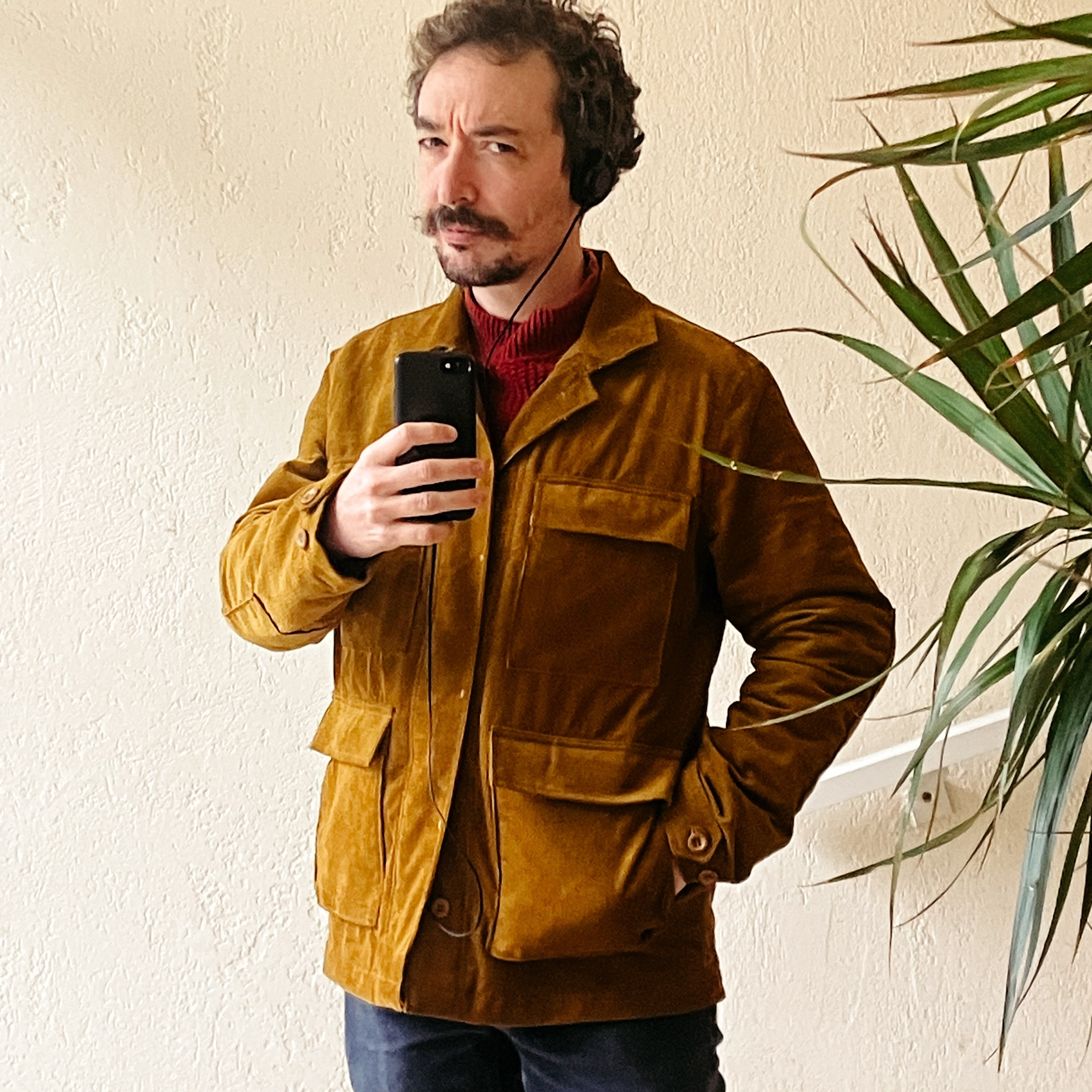 selfie dans un miroir d’un himme qui porte une veste en velours côtelé couleur moutarde à l’ancienne