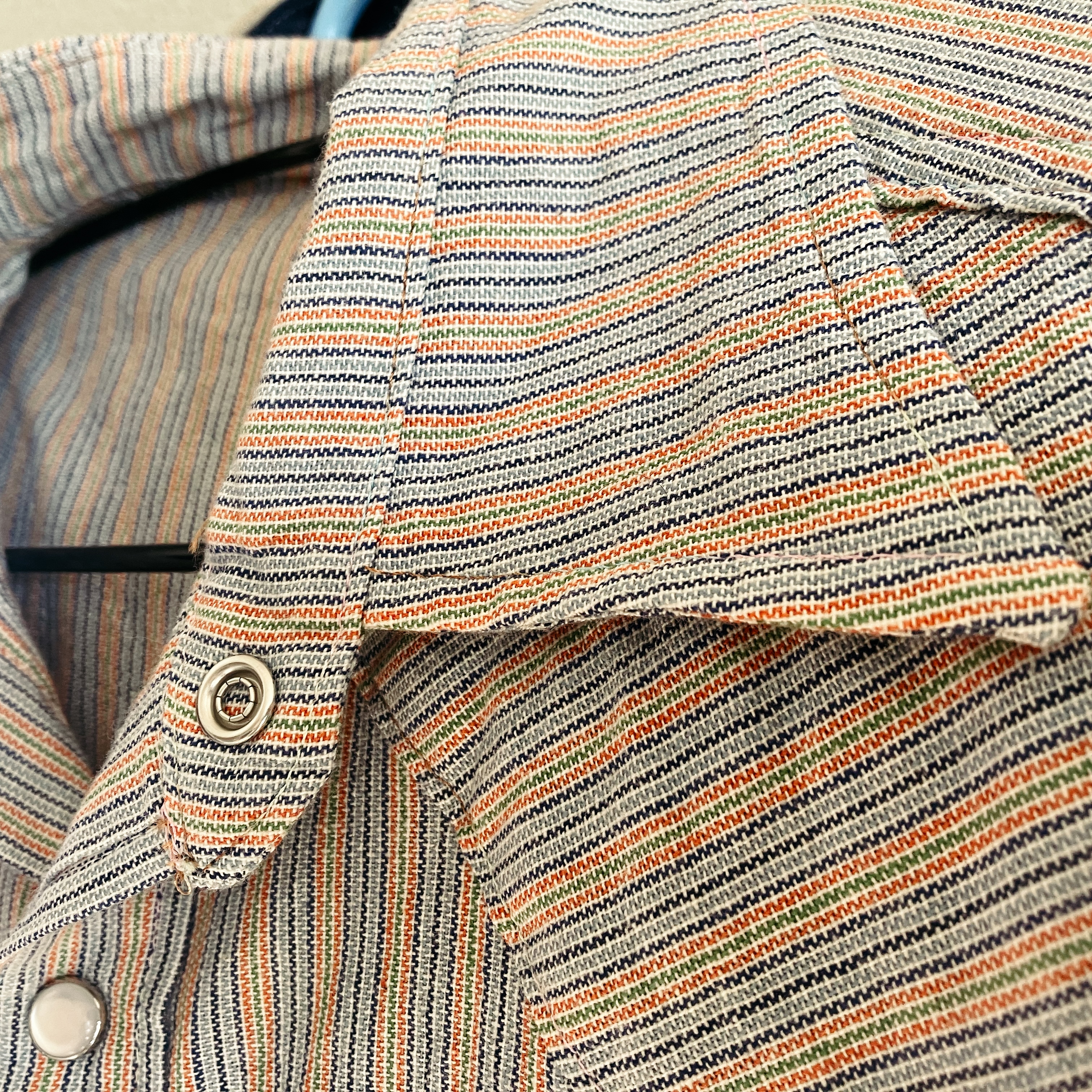 Photo de détail de la chemise précédente, qui montre que les fils visibles du vêtement ont une couleur qui varie entre plusieurs nuances.