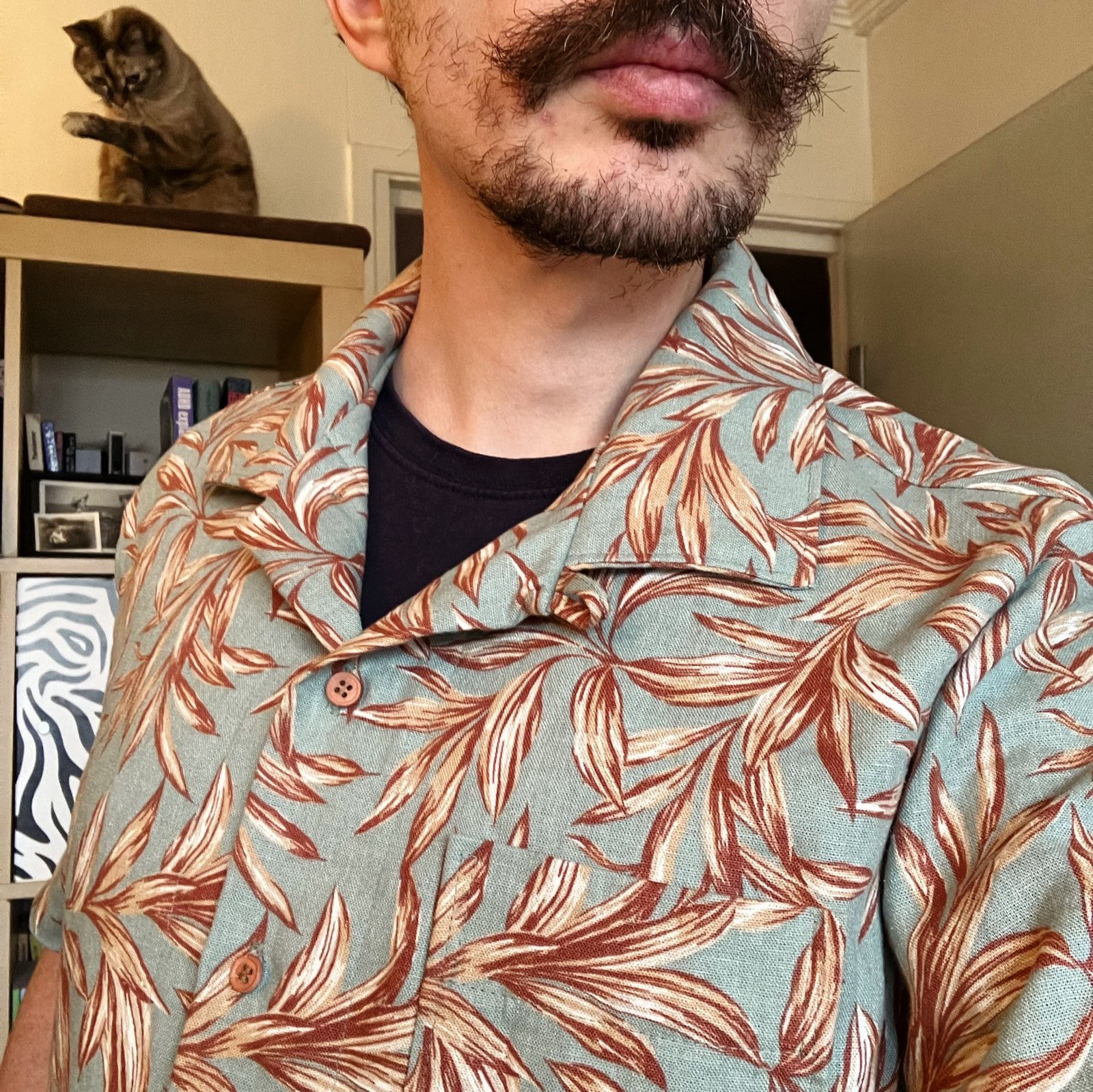Selfie d’un homme avec une chemise fantaisie verte à motifs de feuilles rouille.