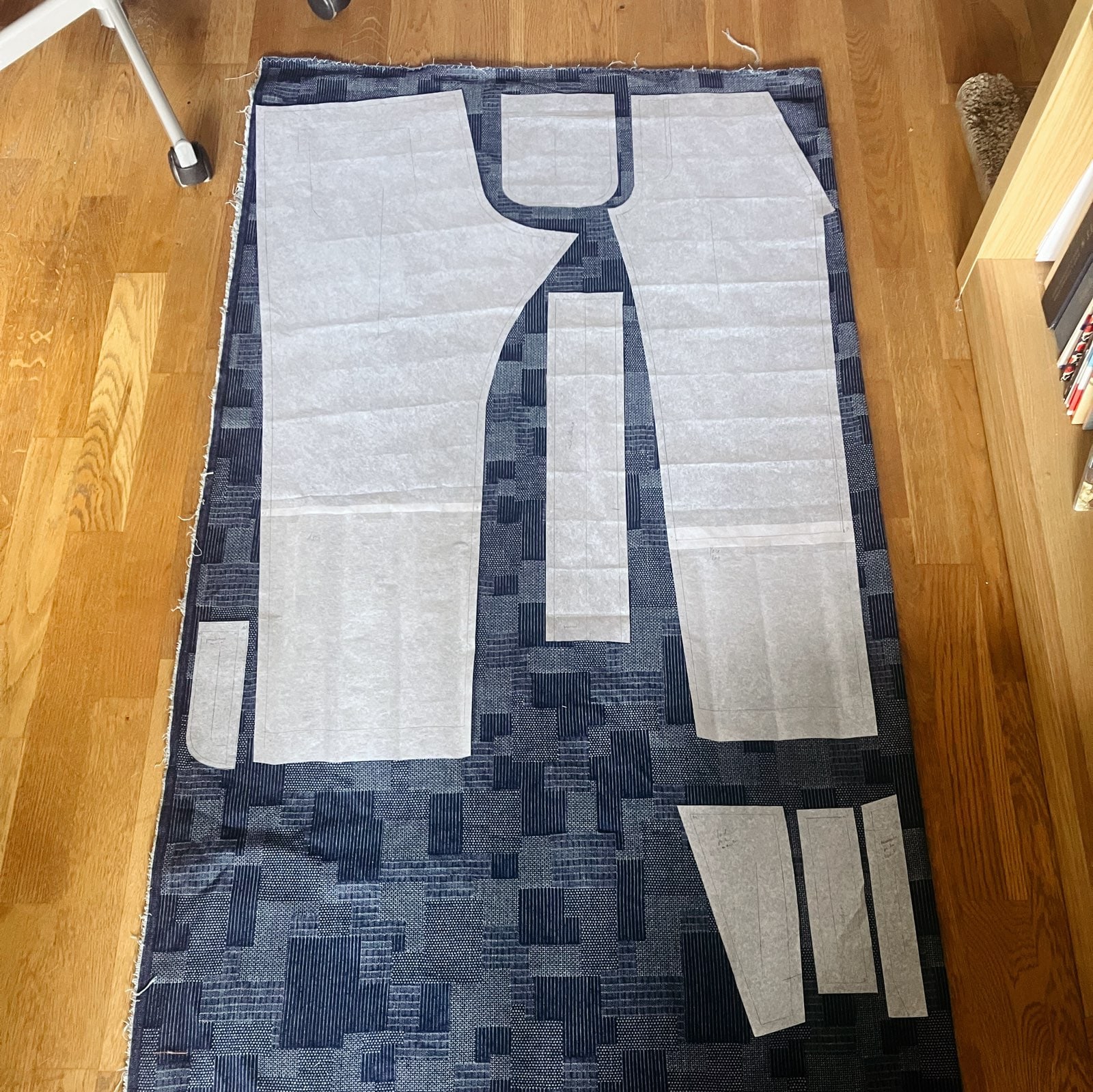 Une pièce d'étoffe sur le sol, avec des morceaux de patrons disposées en vue d’être découpées