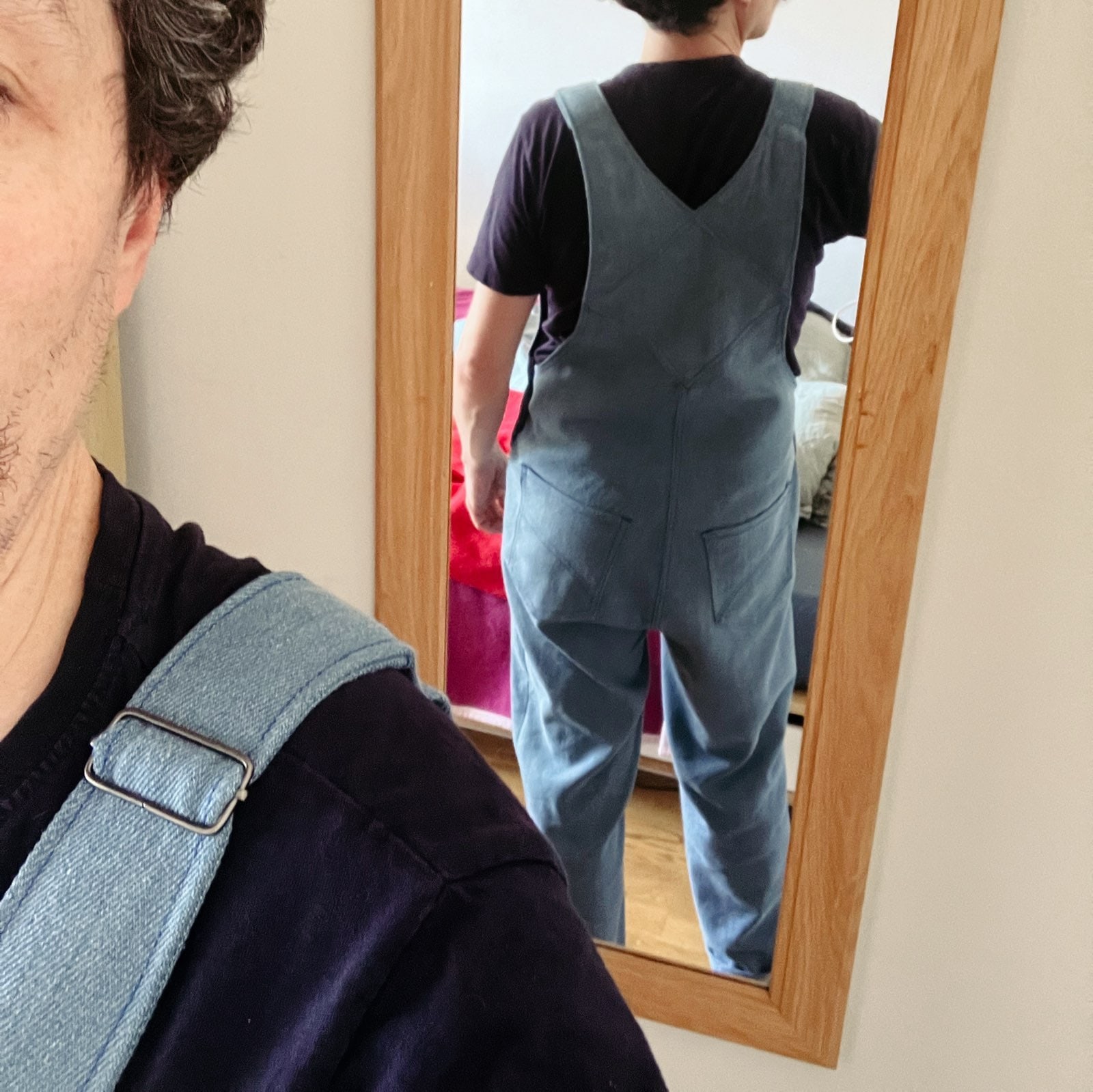 photo d’un homme dans un miroir, on voit le dos de sa salopette bleue clair en jeans